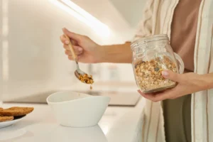 mujer en su cocina sirviendo avena en un tazón para el desayuno como parte de su dieta para el colon irritable